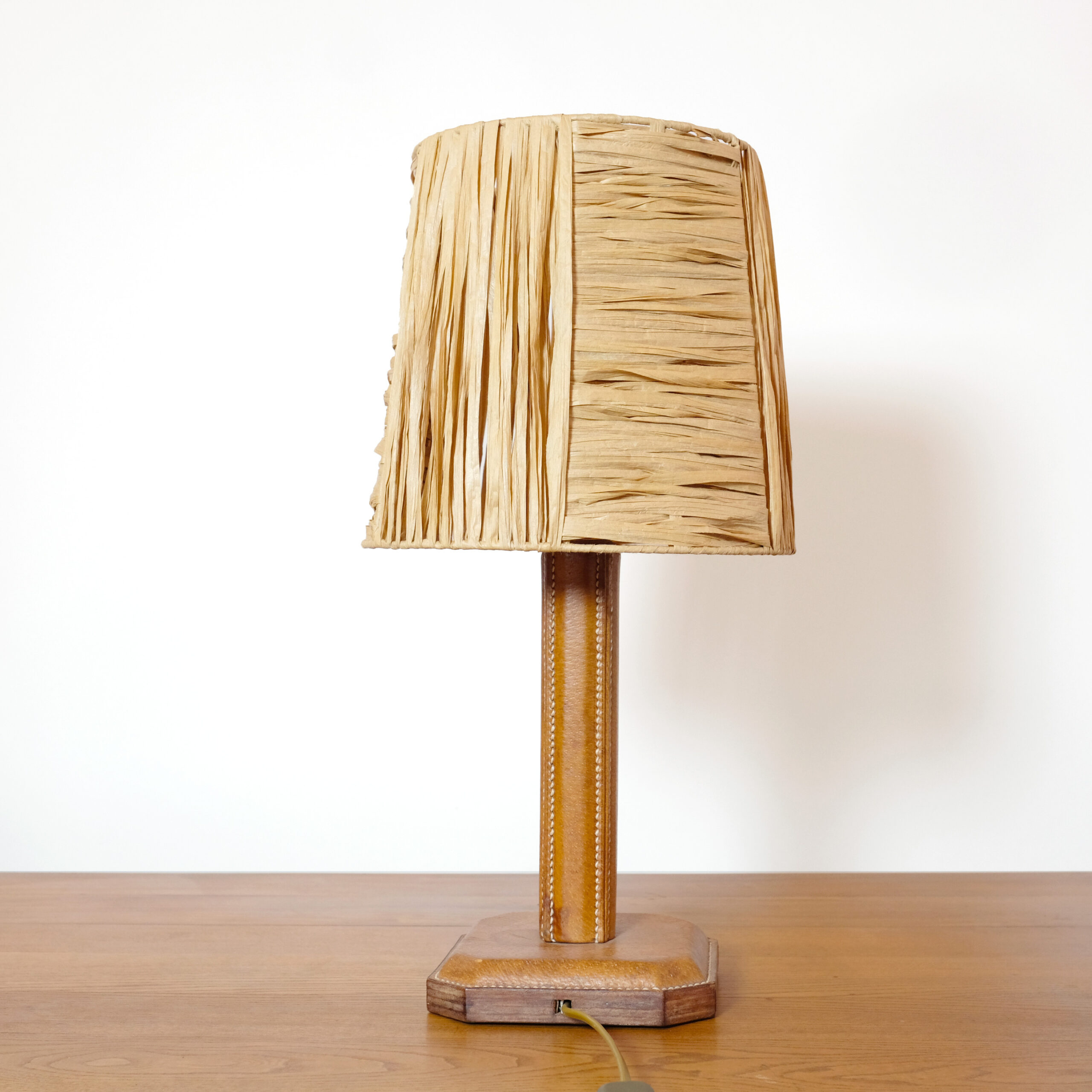 Pied de lampe en cuir piqué sellier et abat-jour en raphia.
